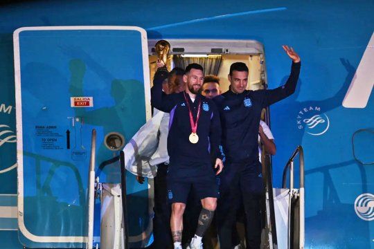 Lionel Scaloni y Leonel Messi bajan del avión con la Copa del Mundo.