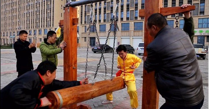 Uno de los estudiantes del Maestro chino de Kung Fu recibe un golpe de un ariete hecho de tronco en su entrepierna 