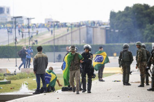 Fuerzas de seguridad detienen a un seguidor de Bolsonaro afuera del Congreso Nacional de Brasil.
