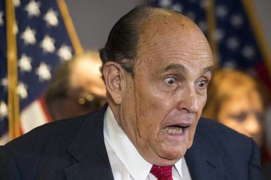 Instante en que una gota marrón atraviesa el rostro de Rudolph Giuliani 